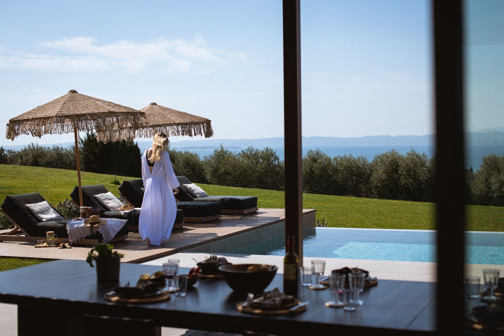 Infinity-Pool der Residenza mit Sonnenschirm und weitem Panorama über den Gardasee